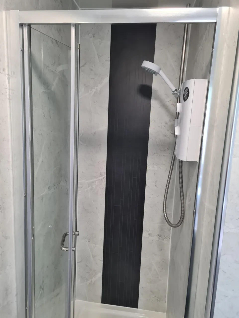 Power Shower Pump Replacement in Kirkcaldy and Fife: Electric shower installed in a quadrant-style enclosure with grey marble-effect panels