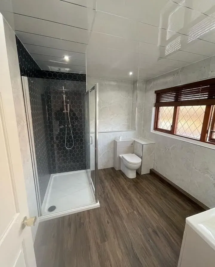 Fitted bathroom with hexagon-tiled shower enclosure, back-to-wall toilet unit and wood-effect flooring