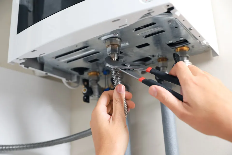 Boiler Repairs & Breakdowns in Kirkcaldy and Fife: Engineer tightening a boiler pipe fitting with pliers during a boiler repair