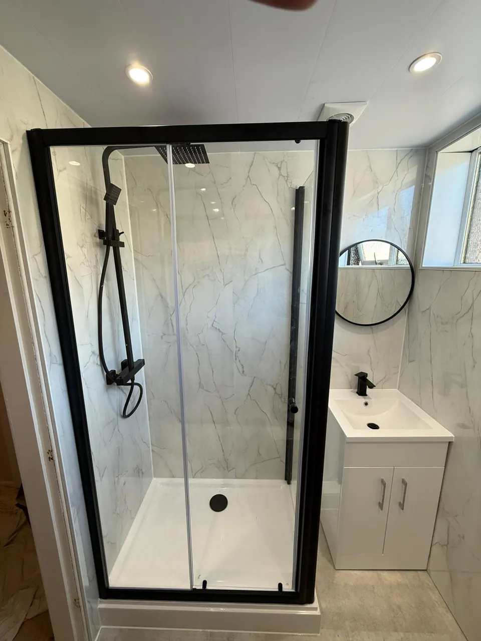 Shower room fitting with black-framed enclosure, matte black thermostatic shower and white vanity